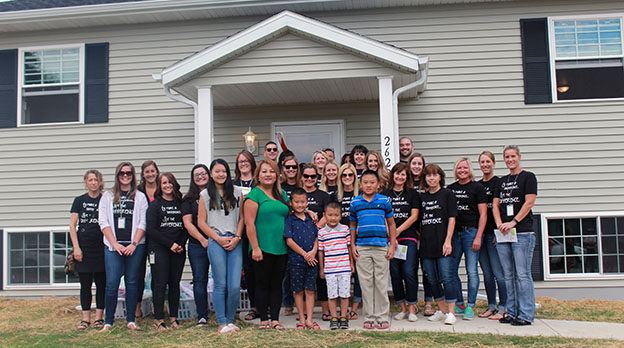 A group of Integrity Insurance team members standing with the Vang Family in front of the Habitat for Humanity home.